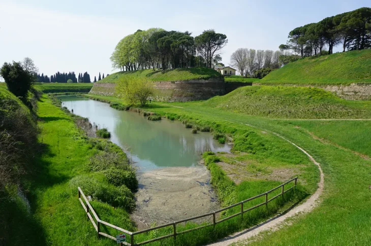 Fossato dei bastioni di Palmanova, tra prati verdi e alberi.