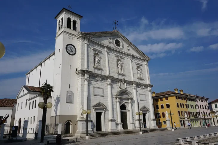 Facciata bianca del Duomo Dogale di Palmanova, con il campanile e l’orologio.