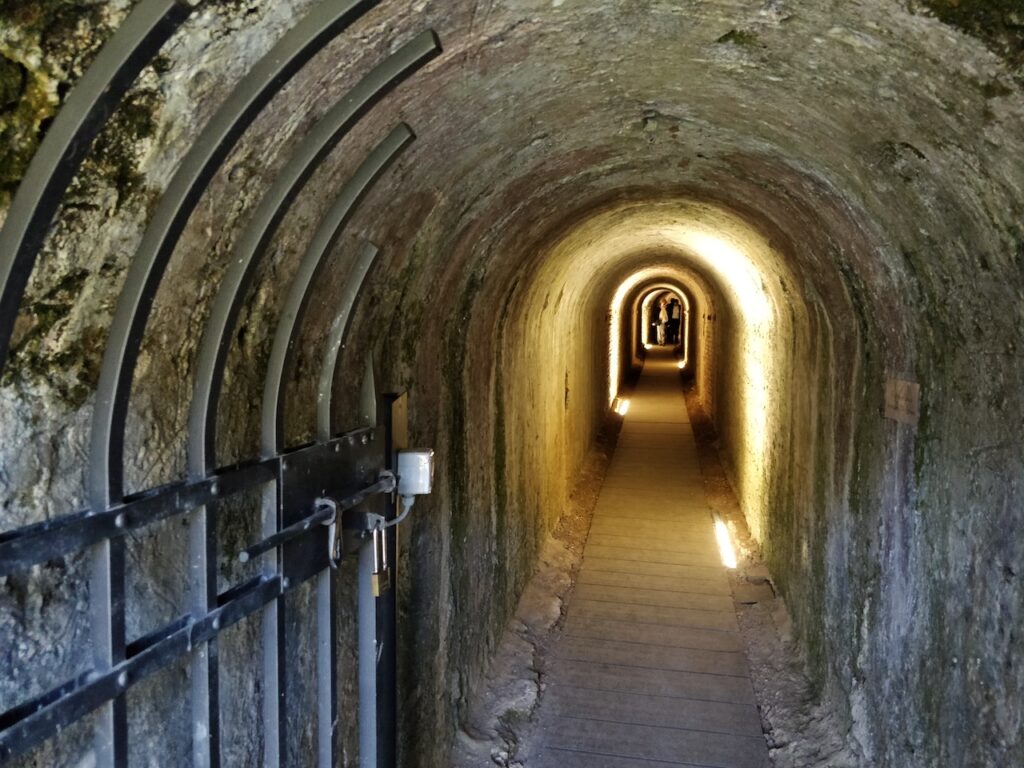 Galleria di contromina con volta in mattoni e camminamento illuminato.