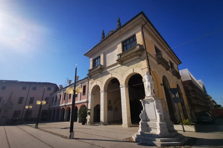 Loggia della Gran Guardia, con portico ad archi e monumento sulla piazza.