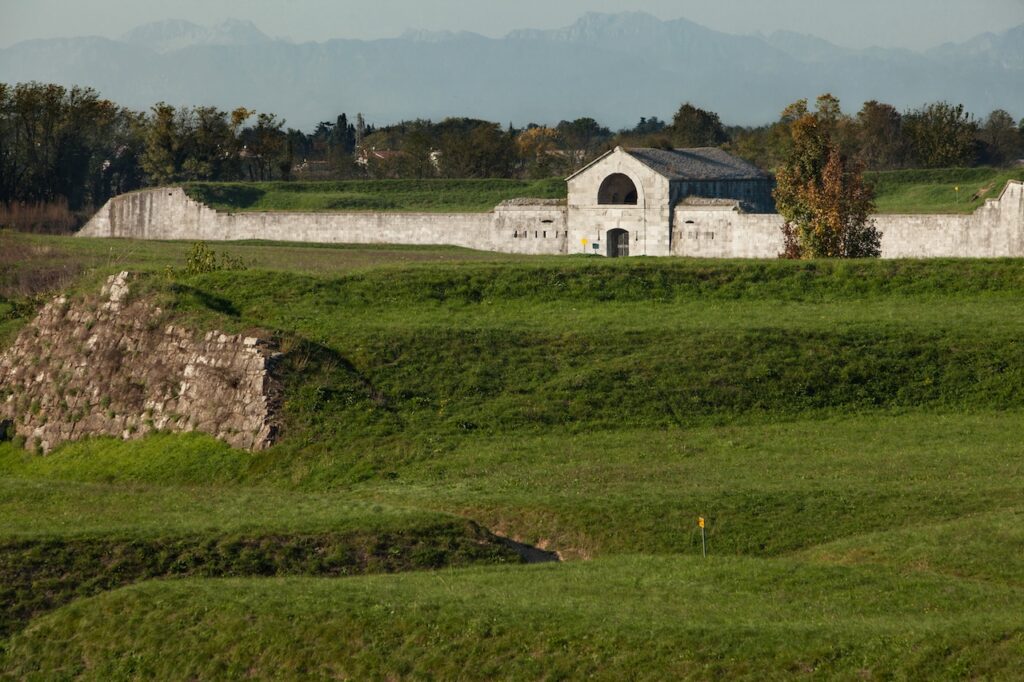 Lunetta napoleonica con un piccolo edificio in pietra tra terrapieni erbosi.