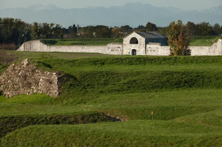 Lunetta Napoleonica tra terrapieni erbosi, con un piccolo edificio in pietra.