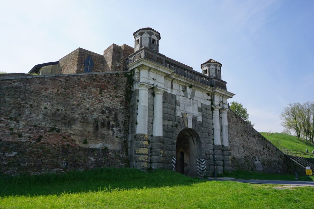 Porta Cividale, con il portale in pietra e la torre dell’orologio sopra le mura.