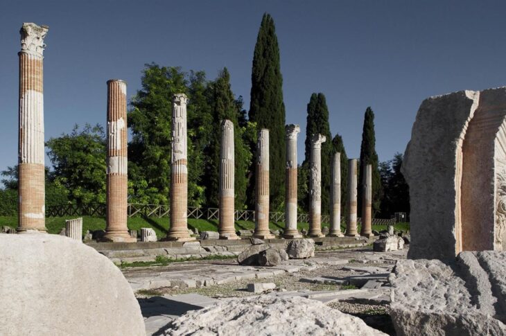 Colonne antiche del foro romano di Aquileia, accanto a un filare di cipressi.