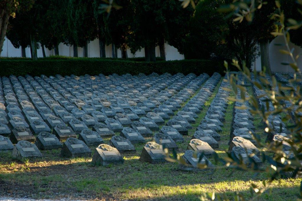 File di lapidi nel cimitero austro-ungarico, sotto gli alberi.