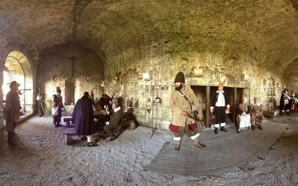 Visitatori con visori per realtà virtuale in una sala con volta in mattoni.