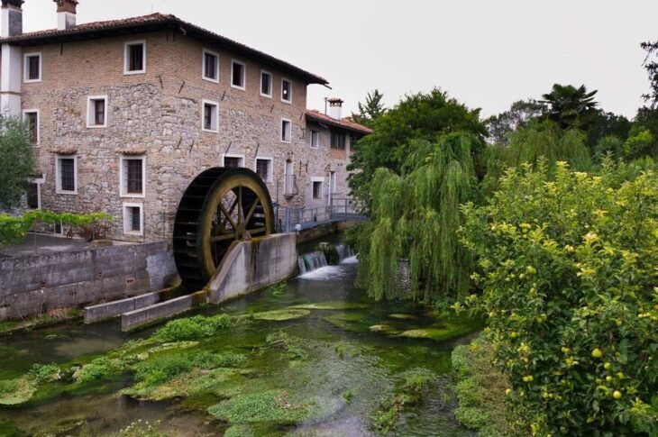 Antico mulino di Strassoldo con ruota ad acqua, accanto a un canale.